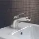 Bidetarmatur in Chromoptik mit einem Hebelgriff und drehbarem Auslauf, installiert auf einem weißen Waschtisch. Marke Ideal Standard. Hintergrund mit dunklen Fliesen.